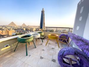 a balcony with chairs and tables and the pyramids at luxurios hotel with pyramids view in Cairo