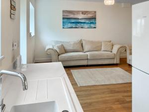 a living room with a couch and a kitchen at White Sands Cottage in Weymouth