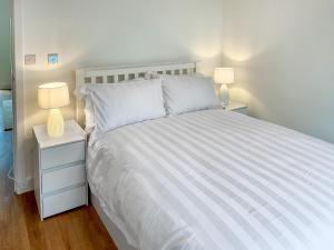 a bedroom with a white bed with two lamps at White Sands Cottage in Weymouth