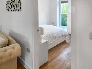 a white bedroom with a bed and a window at White Sands Cottage in Weymouth +3 photos