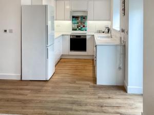 a kitchen with white cabinets and a refrigerator at White Sands Cottage in Weymouth