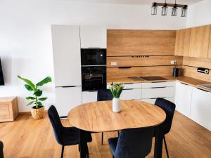 a kitchen with a wooden table and black chairs at Apartmán Viktória in Poprad