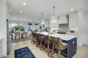 a kitchen with white cabinets and a blue island with chairs at Cabana Blu in Captiva