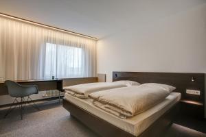 a bedroom with a bed and a desk and a chair at eXo Fly Level 4 Hotel Stuttgart-Flughafen in Ostfildern +28 photos