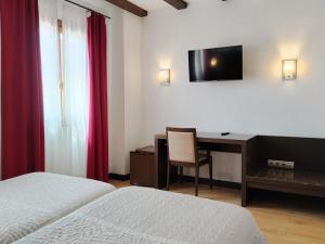a bedroom with two beds and a desk and a television at Hotel Rey Sancho in Navarrete