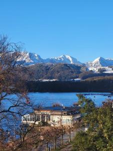 a large building on a lake with snow covered mountains at Penthouse Panorama Seeblick in Gmunden