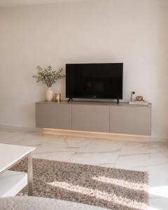 a living room with a flat screen tv on a white wall at Maluno vilos apartamentas su terasa in Palanga