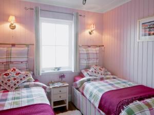two beds in a small room with pink walls at Dunultach Cottage in Ronachan