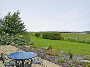 a patio with a table and chairs in a garden at Dunultach Cottage in Ronachan +5 photos
