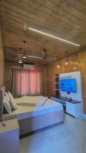 a bedroom with a large bed and a flat screen tv at Tranquil Nature Resort in Rāipur