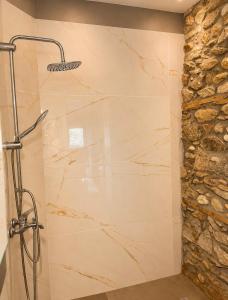 a shower in a bathroom with a stone wall at Βίλα Βασιλική in Elassona +20 photos