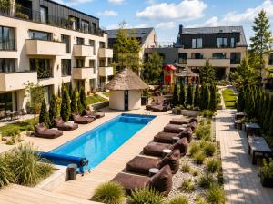 an outdoor pool with lounge chairs and a hotel at Maluno vilos apartamentas su terasa in Palanga