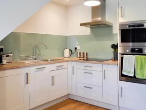 a kitchen with white cabinets and a sink at Little Cottage in Wigtown