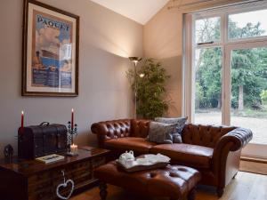 a living room with a leather couch and a table at The Coach House in Great Malvern