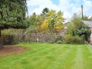 a backyard with a stone fence and a grass yard at The Coach House in Great Malvern