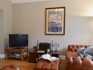 a living room with two leather chairs and a flat screen tv at The Coach House in Great Malvern +3 photos