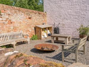 a patio with two benches and a fire pit at Cleugh Foot in Longtown