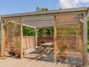 a wooden pergola with a picnic table on a deck at Cleugh Foot in Longtown