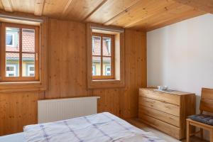 a bedroom with wooden walls and a bed and two windows at Ferienwohnung Stadthaus in Mellrichstadt