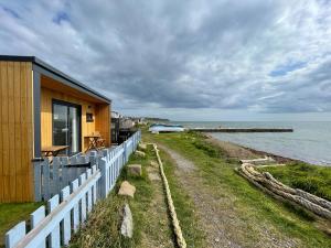 a house with a fence next to the ocean at Sunrise Summerhouse in Hilton of Cadboll