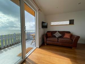a living room with a couch and a view of the ocean at Sunrise Summerhouse in Hilton of Cadboll +11 photos