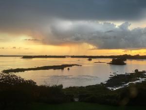 a sunset over a river with islands in the water at Corrib View Country House in Killarone