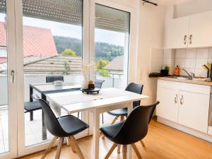 a kitchen with a table and chairs and a large window at Gemütliches Apartment 8 am Titisee mit Balkon, Top Lage, Parkplatz in Titisee-Neustadt +9 photos
