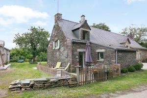 an old stone house with a fence and chairs at Gîte La P'tite Longère in Saint-Jacut-les-Pins