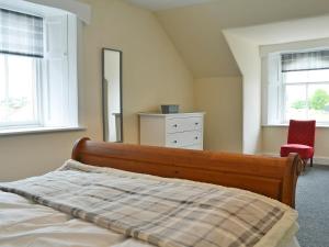 a bedroom with a bed and a dresser and two windows at Halleaths Home Farm in Lochmaben
