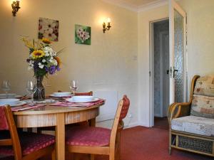 a dining room table with a vase of flowers on it at New Meadows Cottage in Pickering
