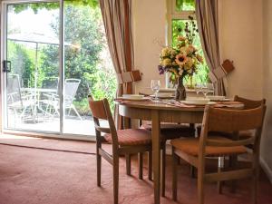 a dining room table with chairs and a vase of flowers at New Meadows Cottage in Pickering
