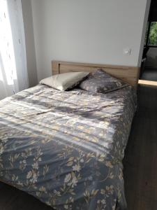 a bed in a bedroom with a blue comforter at Une pause au pied des Pyrénées in Asson