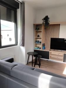 a living room with a couch and a tv at Une pause au pied des Pyrénées in Asson