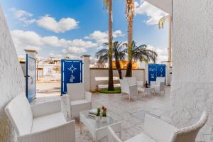 a patio with white chairs and palm trees at B&B Gioia del Mare in Torre Lapillo