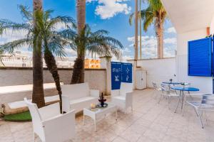 a patio with palm trees and a table and chairs at B&B Gioia del Mare in Torre Lapillo