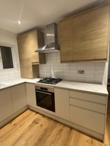 a kitchen with white counter tops and wooden cabinets at The Modern Retreat in Barnet