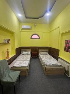 a room with two beds and a chair in it at Dom Hostel in Samarkand