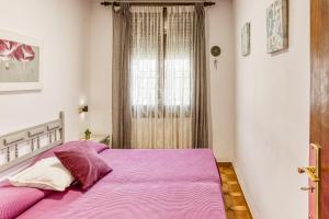 a bedroom with a bed with purple sheets and a window at Bahia Studio in Empuriabrava