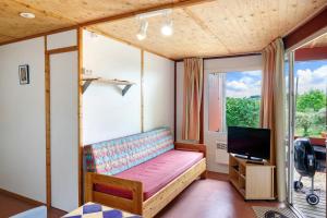 a small bedroom with a bed and a tv at Chalet Le Chene Vert in Salignac Eyvigues