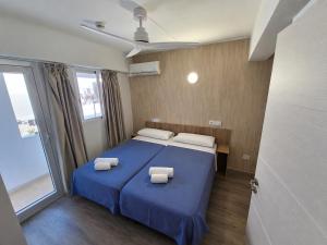 a bedroom with a blue bed with two towels on it at Hostal Sol de Mallorca in El Arenal +7 photos
