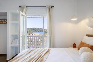 a bedroom with a bed and a large window at Kastri Houses in Panormos Skopelos