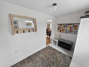a living room with white walls and a mirror at Seaside Serendipity Cottage in Herring Neck +25 photos