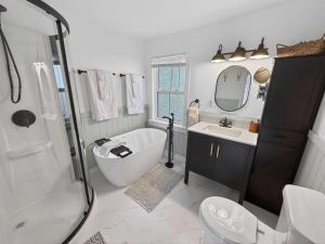 a bathroom with a tub and a toilet and a sink at Seaside Serendipity Cottage in Herring Neck