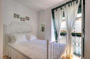 een slaapkamer met een wit bed en een raam bij Stay local in Alfama! Alice central home, near river in Lissabon