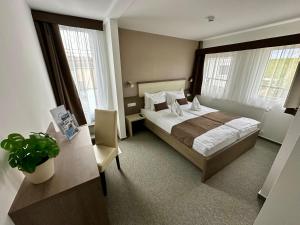 a hotel room with a bed and a desk and windows at Tündérfátyol in Abádszalók