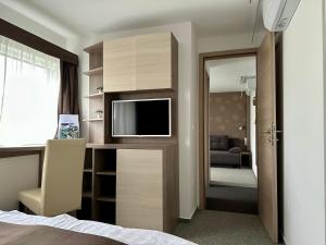 a hotel room with a bed and a tv in a room at Tündérfátyol in Abádszalók
