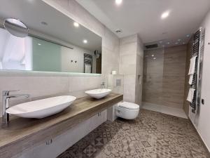 ein Badezimmer mit zwei Waschbecken, einer Toilette und einem Spiegel in der Unterkunft Hotel Nereida in L'Estartit + 59 Fotos