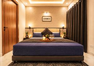 a bedroom with a large bed with a blue bedspread at Ace Stayz - Boutique Hotel Near DLF Mall Sector 45, Noida in Noida