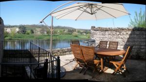 a wooden table and chairs with an umbrella on a patio at Les Terraces Sur La Dordogne in Sainte-Foy-la-Grande