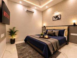 a bedroom with a bed with blue sheets and a tv at Ace Stayz - Boutique Hotel Near DLF Mall Sector 45, Noida in Noida +40 photos